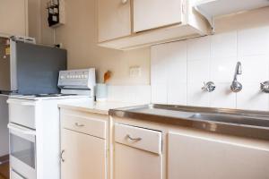 una pequeña cocina con fregadero y nevera. en Light-Filled Paddington Studio with Parking en Sídney
