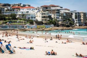 een groep mensen op een strand met gebouwen bij Stylish Sun Drenched North Bondi Beach Oasis in Sydney