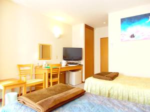 um quarto de hotel com uma secretária e um quarto com uma cama e uma televisão em Forest Villa YUMESUZU フォレストヴィラ夢寿々 em Kaizu