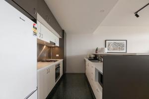 a kitchen with white cabinets and a black counter top at Treetops Camperdown Inner City Bliss w Parking in Sydney
