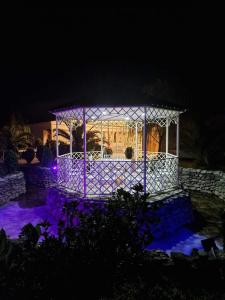 un gazebo illuminato di notte con luci viola di Hotel Oasis Villa a Tsqaltubo