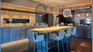 a kitchen with a long bar with blue bar stools at Hotel Der Einrichter in Straubing