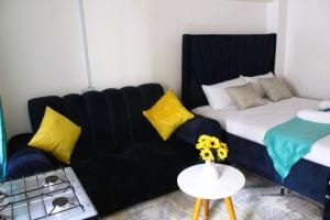 een woonkamer met een zwarte bank en een bed bij ZenNest Studio in Naivasha