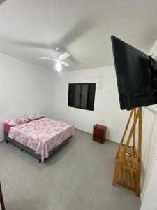 1 dormitorio con 1 cama y TV de pantalla plana en Pousada e Espaco AURORA Peruibe, en Peruíbe