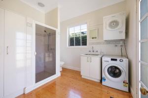 a bathroom with a washing machine and a shower at Thyme Cottage Warrnambool in Warrnambool