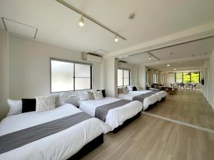 uma fila de camas num quarto em bHOTEL Kaniwasou 201 2BR Apt, Near Itsukushima Shrine, For 12 Ppl em Hatsukaichi