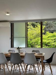 ein Esszimmer mit einem Tisch und Stühlen sowie einem großen Fenster in der Unterkunft bHOTEL Kaniwasou 201 2BR Apt, Near Itsukushima Shrine, For 12 Ppl in Hatsukaichi