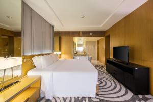 a bedroom with a white bed and a flat screen tv at Centara Grand at Central Plaza Ladprao Bangkok in Bangkok