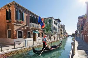 a man is paddling a gondola down a canal at Hotel Messner in Venice