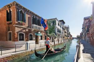 Un uomo sta remando su una gondola lungo un canale di Hotel Messner a Venezia
