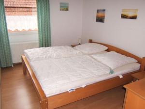 Schlafzimmer mit einem Bett mit weißer Bettwäsche und einem Fenster in der Unterkunft Holiday apartment with a garden in Horumersiel