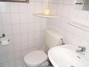 een witte badkamer met een toilet en een wastafel bij Holiday apartment with a garden in Horumersiel