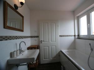 a bathroom with a sink and a tub and a mirror at To"n Lüchtfüer Comfortable holiday residence in Dwarsdorf +36 photos