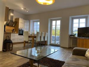 een woonkamer met een glazen tafel en een keuken bij Wingertsblick Modern retreat in Graach