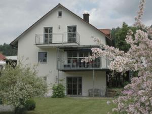 a white house with a balcony and flowering trees at Holiday home Altmühltal in Beilngries