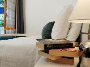 a stack of books on a bed with a lamp at HoliHome_La Sirena 50m dal Mare in Tortoreto Lido