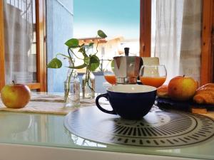 a cup of coffee sitting on a glass table with apples at HoliHome_La Sirena 50m dal Mare in Tortoreto Lido