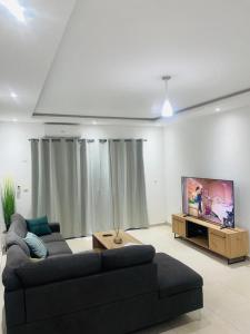 sala de estar con sofá y TV de pantalla plana en RESIDENCE MH SERVICES Abidjan en Abiyán
