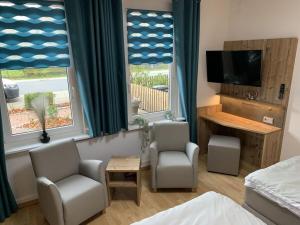 a bedroom with two chairs and a tv and two windows at Amazing holiday home near the lake in Hambühren