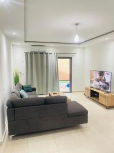 ein Wohnzimmer mit einem Sofa und einem TV in der Unterkunft RESIDENCE MH SERVICES Abidjan in Abidjan