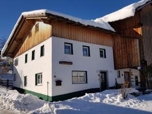 un gran edificio blanco con nieve en el suelo en Uitzicht op Rachel, en Untermitterdorf