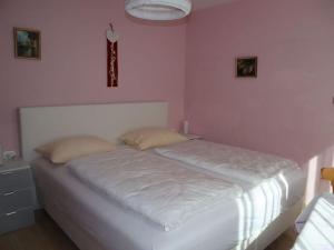 a white bed in a bedroom with a pink wall at Columbine Modern Retreat in Carezza al Lago