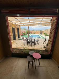 Zimmer mit einem Tisch, Stühlen und einem Pool in der Unterkunft شاليه البحر الميت الرامة-Deadsea in Al Rama