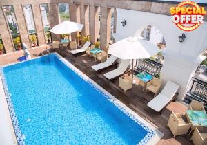 an overhead view of a swimming pool with chairs and umbrellas at Danaciti Hotel in Danang