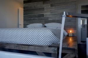 Couples Getaway on Bruny Island في Alonnah: غرفة نوم بسرير مع جدار خشبي