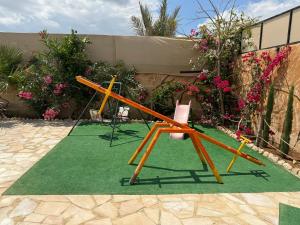 dos sillas y un columpio en una alfombra verde en شاليه البحر الميت الرامة-Deadsea, en Al Rama