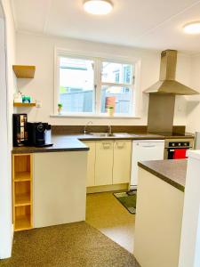 eine Küche mit weißen Schränken und einem Waschbecken in der Unterkunft Comfy & Sunny home in Wellington in Wellington