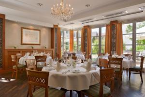 a restaurant with white tables and chairs and a chandelier at Hotel Weisses Lamm in Veitshöchheim