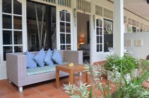 een veranda met een rieten bank en een tafel bij Little Pond Homestay in Sanur