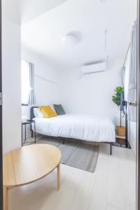 a white bedroom with a bed and a table at 67 Apt Koenji Tokyo in Tokyo