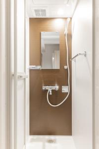 ein Bad mit einer Dusche und einem Spiegel in der Unterkunft 67Hotel Koenji Tokyo in Tokio