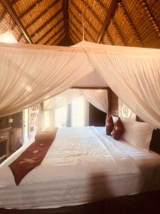 1 dormitorio con cama blanca y mosquitera en La Nusa Penida Homestay by BIJAK, en Nusa Penida