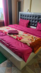 een groot bed met een rood dekbed erop bij Hotel Sunrise Inn & Restaurant, Kanatal in Chamba