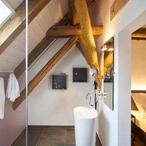 ein Badezimmer mit einem weißen Waschbecken und Holzdecken in der Unterkunft Yard Boarding Hotel Wolfsburg in Wolfsburg