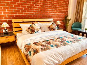 Bett in einem Zimmer mit Ziegelwand in der Unterkunft The Pine Woods - A Four Star Luxury Resort in Mussoorie in Masuri
