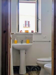 een badkamer met een wastafel, een toilet en een raam bij Loft le dueffe al capo in Palermo