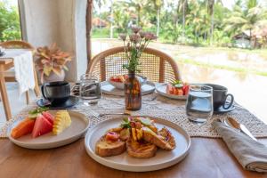 - une table avec deux assiettes de produits pour le petit-déjeuner et des fruits dans l'établissement Villa Rabita, à Ubud