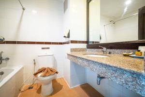 ein Badezimmer mit einem WC, einem Waschbecken und einem Spiegel in der Unterkunft J A Plus Hotel in Pattaya