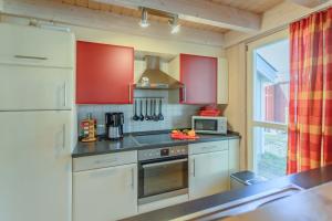 a kitchen with red cabinets and a stove top oven at Ferienhaus Seepferdchen in Baabe