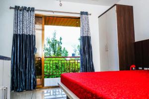 a bedroom with a red bed and a large window at HOTEL SAMRUDDHI in Panchgani +6 photos