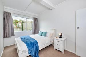 a white bedroom with a bed and a window at Bright Kingsland Contemporary in Auckland