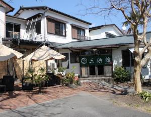 un edificio con una sombrilla delante de él en 三浜館 伊豆大島 en Oshima