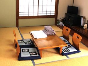 una mesa de madera y sillas en la sala de estar. en 三浜館 伊豆大島 en Oshima