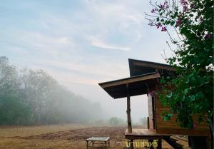 un piccolo edificio con una panchina in un campo di บ้านส่าหรีโฮมสเตย์ a Lan Sak