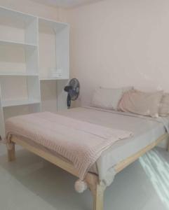 uma cama num quarto branco com ar condicionado em Da Arreglados’ Beach House em Abra de Ilog