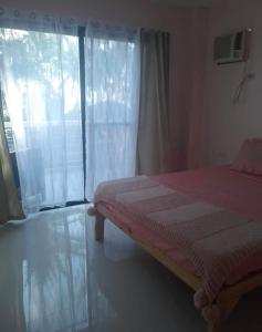 1 dormitorio con cama y ventana grande en Da Arreglados’ Beach House, en Abra de Ilog